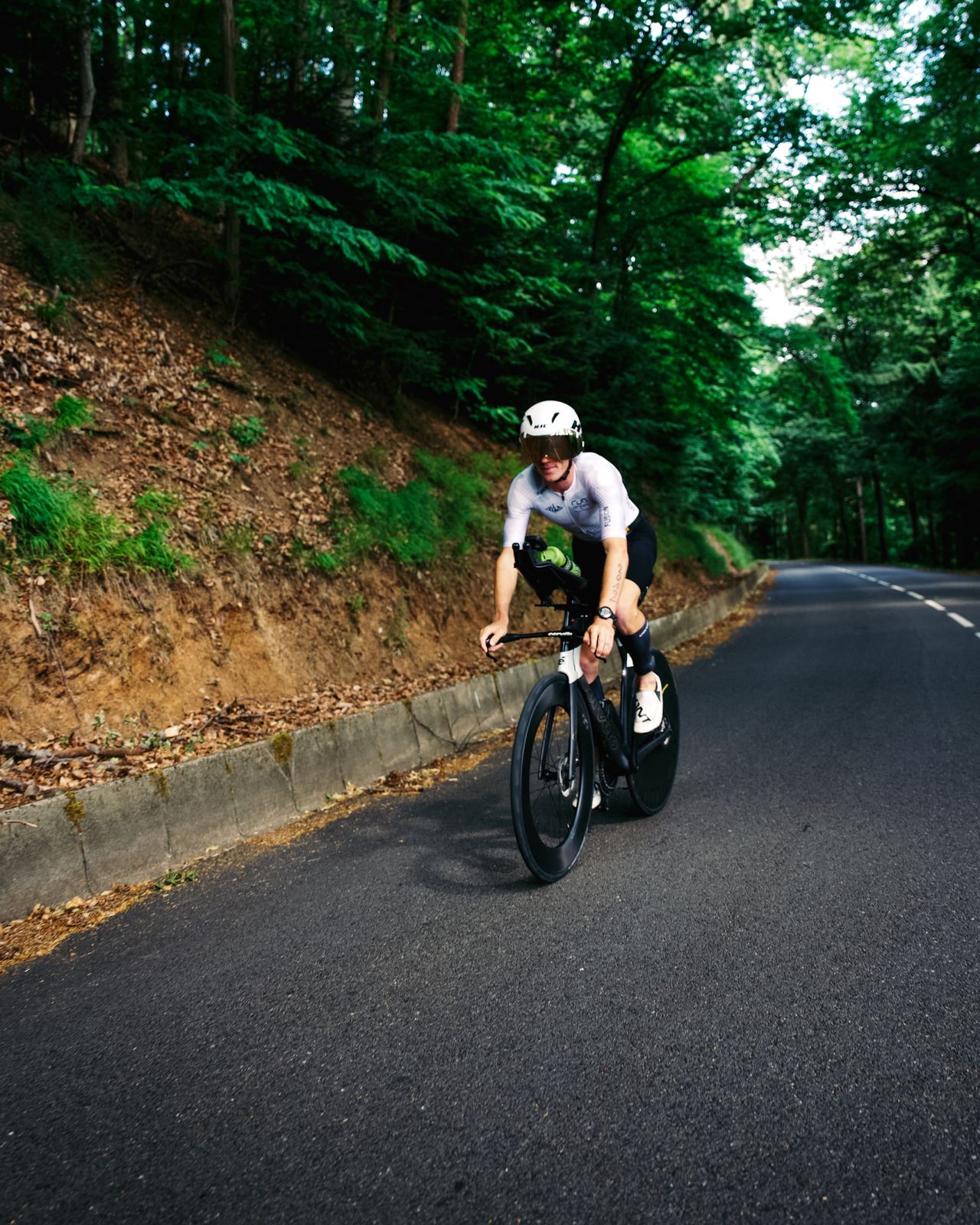 Dorian Muller &agrave; v&eacute;lo sur une route en for&ecirc;t, position a&eacute;rodynamique sur v&eacute;lo Cervelo